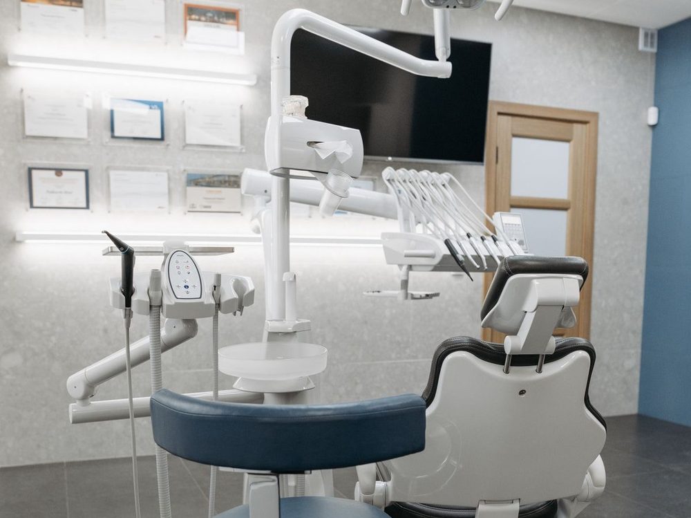 Salle de soins équipée d'un fauteuil dentaire moderne et de son bras d'instruments.