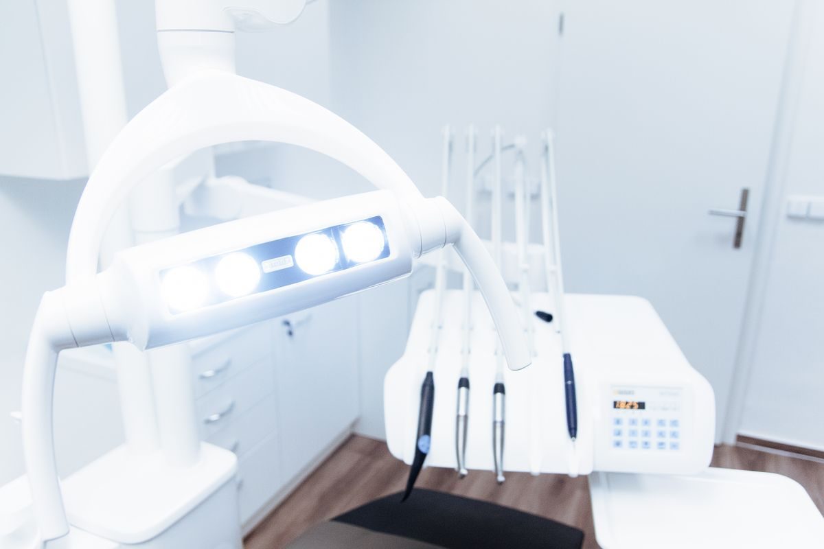 Gros plan sur l'équipement dentaire de pointe utilisé au cabinet : lampe à polymériser, fauteuil et instruments rotatifs.
